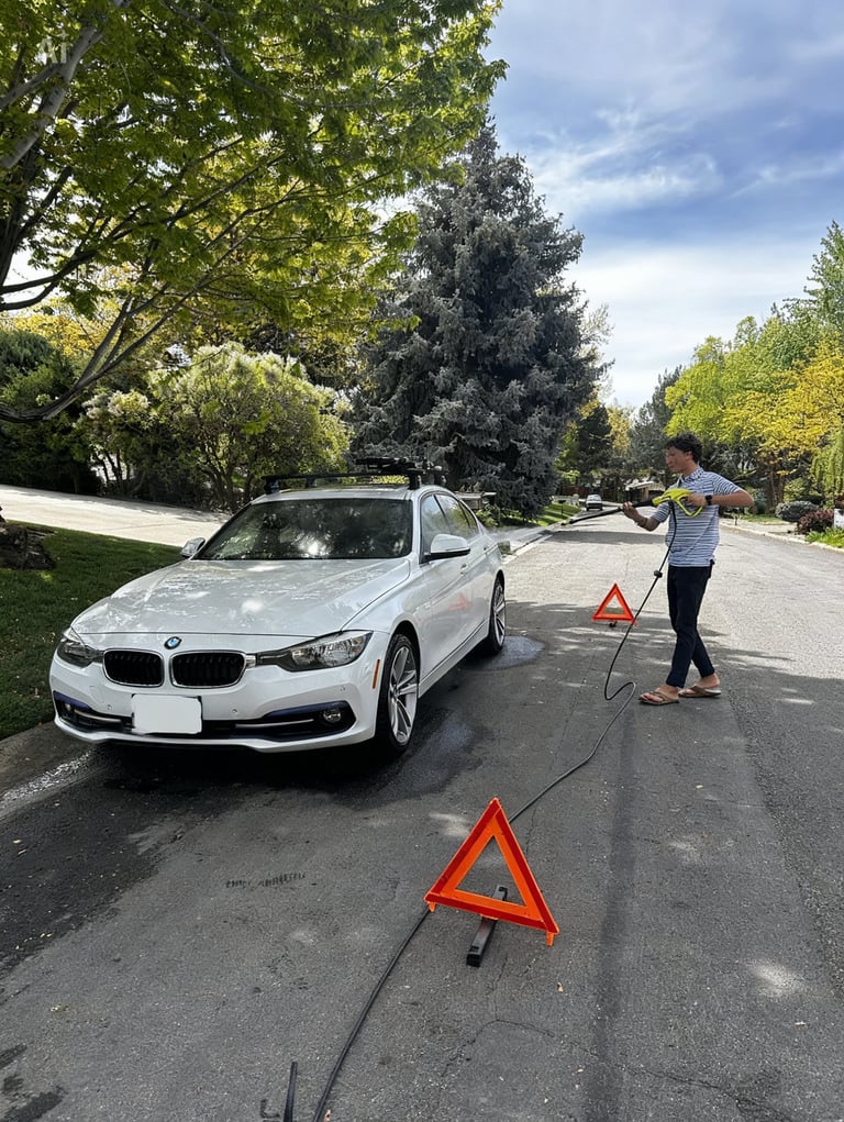 White BMW sedan parked on residential street with emergency warning triangles and person standing nearby
