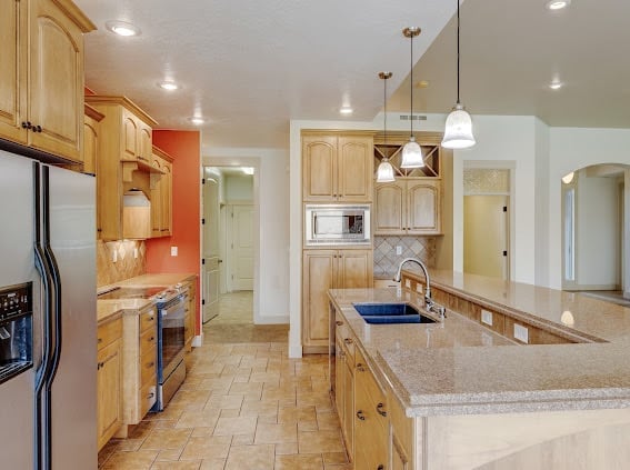 Spacious kitchen with wooden cabinets, stainless steel appliances, granite countertops, and pendant lighting over the island