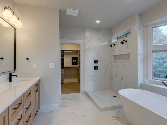 Modern luxury bathroom with marble shower, freestanding tub, floating vanity, and natural light from large window