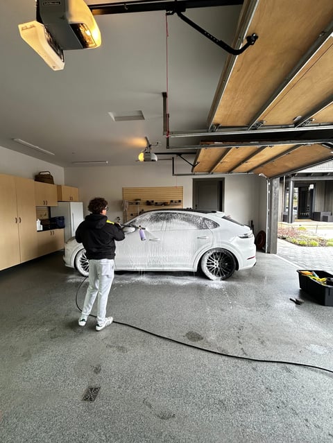 Professional car detailing in modern garage with overhead lighting
