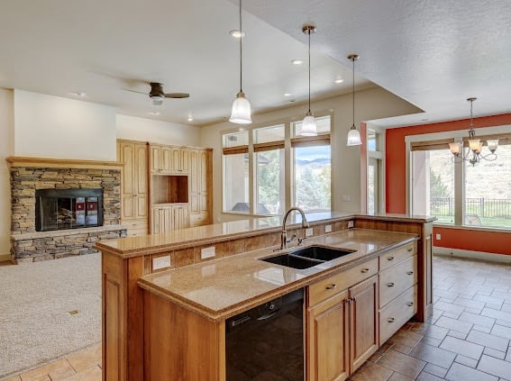 Modern luxury kitchen with large island, granite countertops, stainless steel appliances, pendant lighting, and open floor plan to living areas